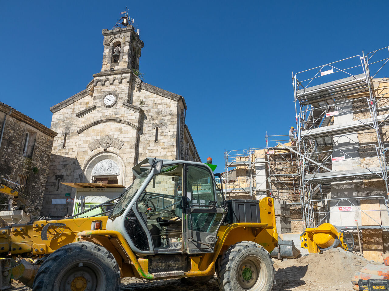 engin de chantier devant le parvis de l'église